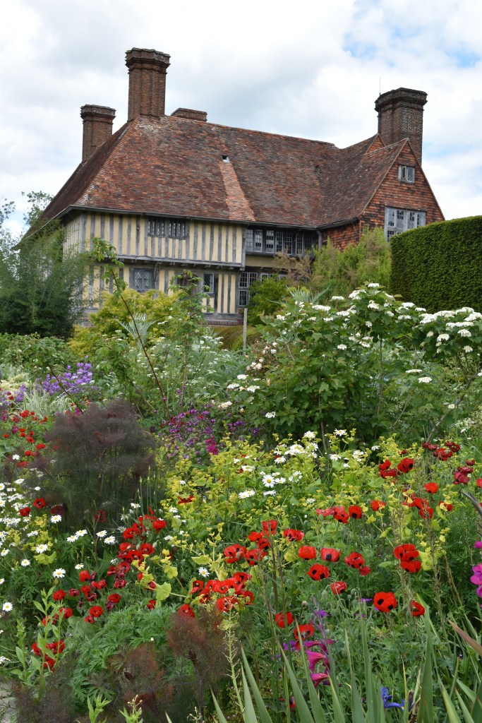 Great Dixter in Sussex, England. The Long Border packed with plants including Ladybird Poppy. Behind the garden is the old house where the well-known garden writer Christopher Lloyd lived for most of his life