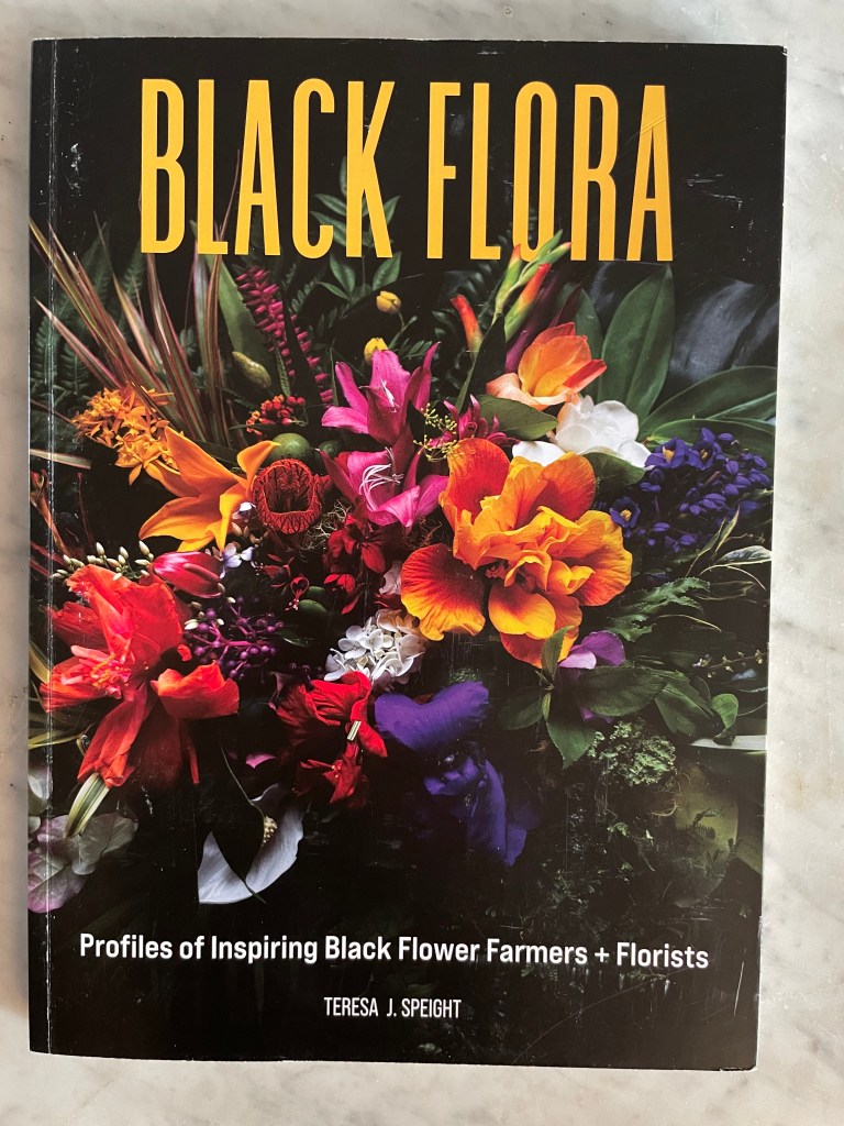 Brightly colored front cover with multi-colored flowers on a black background. Title is Black Flora - a gardening book by Teresa Speight