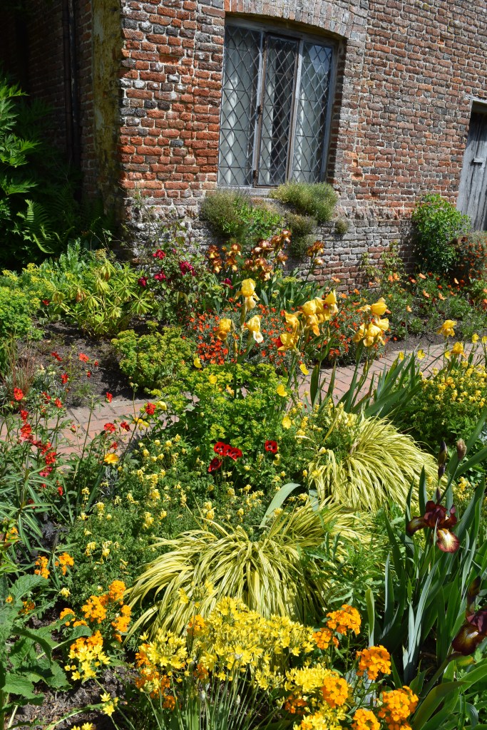 Irises, Geum, and wallflowers sizzle in this bed of hot colored plants