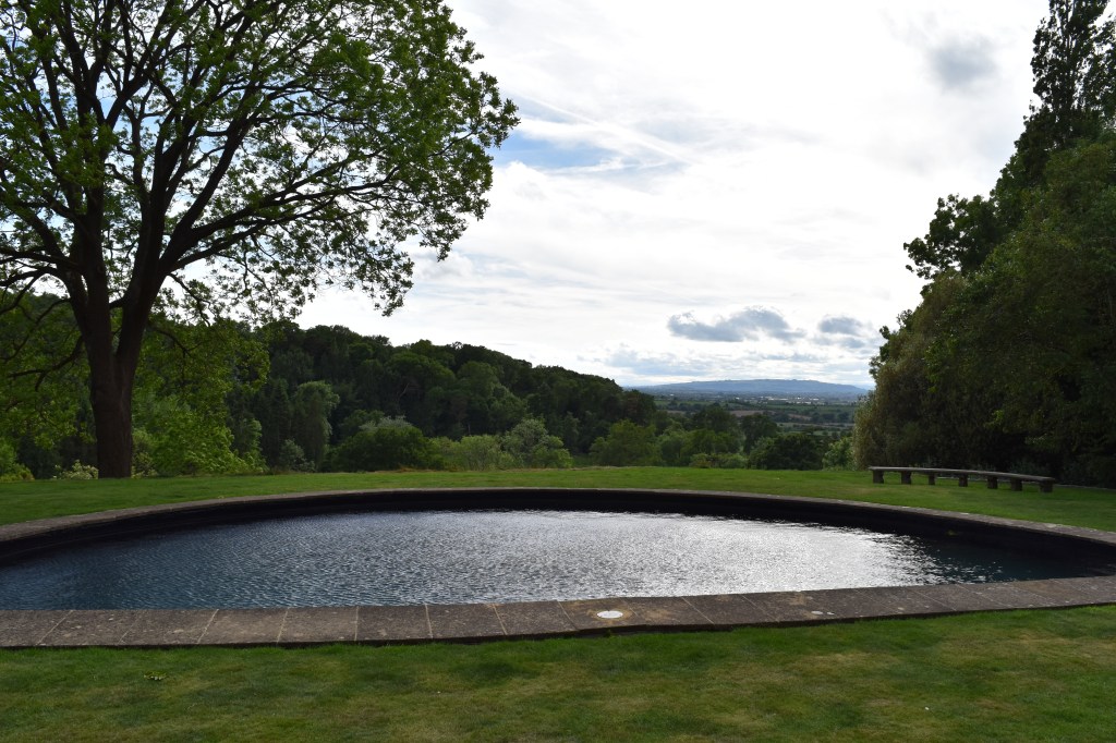 The Lower Garden at Kiftsgate Court Garden with view out over the moon-shaped pool - to the Malvern Hills in the distance.