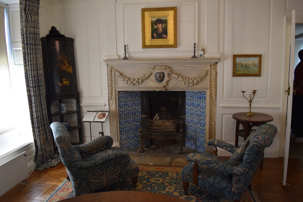 Kelmscott Manor - A cozy parlour with two comfortable chairs near the tiles fireplace.
