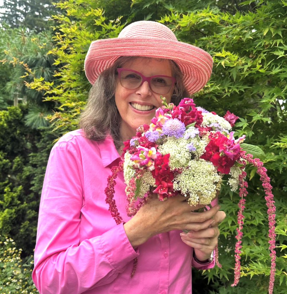 Jenny Rose Carey wearin g a pink shirt and holding a bouquet of flowers in pink and cream