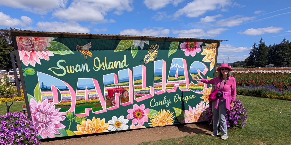 Jenny Rose Carey in front of the big sign advertising Swan Isalnd Dahlias, Canby, Oregon.
