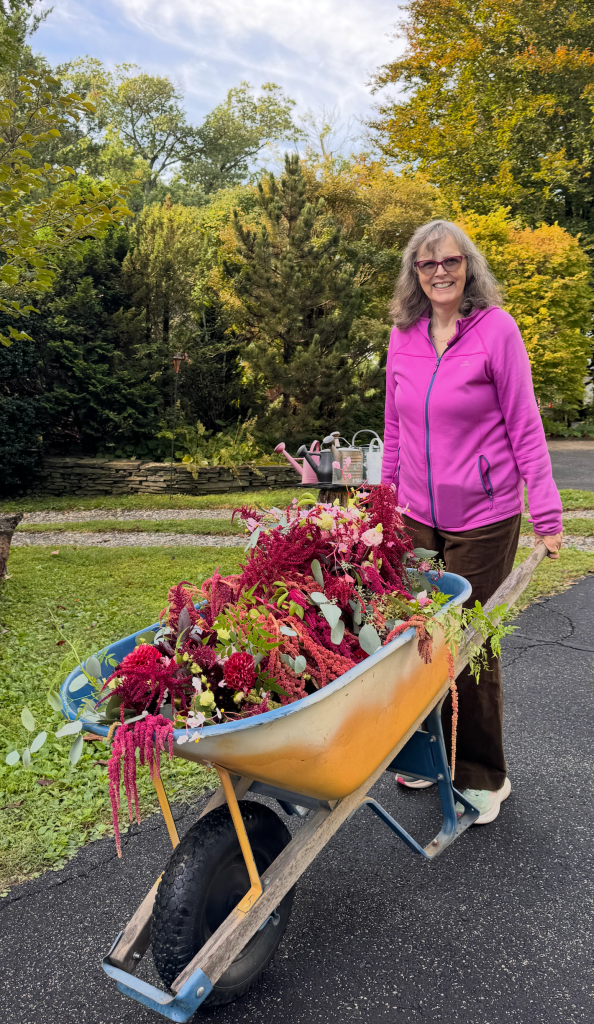 Jenny Rose Carey with flower arrangements in a wheelbarrow